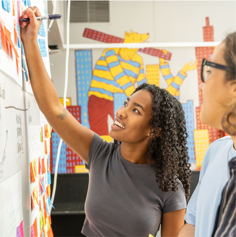 A USC Annenberg student writing on a whiteboard.