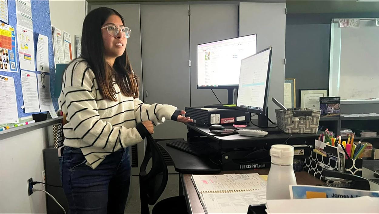 Wendy Chavez stands at a teacher's desk. 